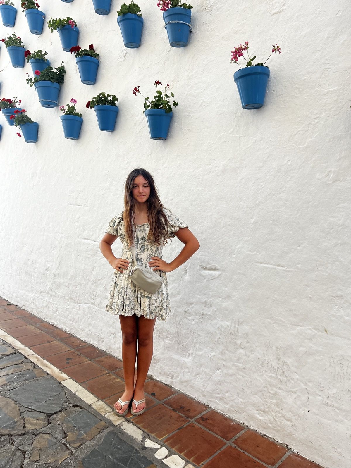 Ruby against a white wall hung with blue flower pots in Marbella