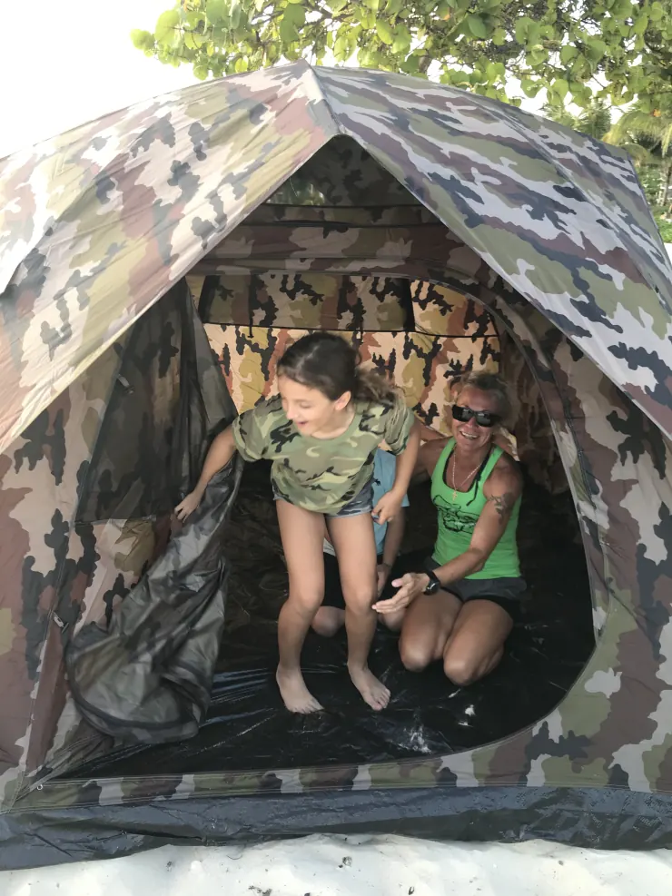 Ruby and her mom laughing inside a camouflage tent on the beach