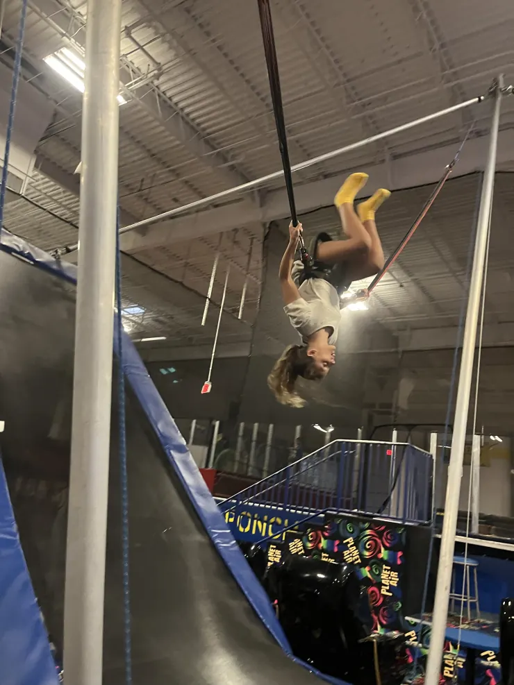 Ruby hanging upside down from a trapeze bar