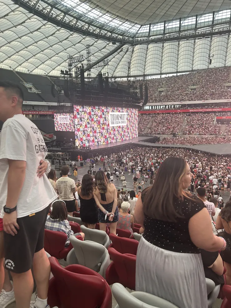 The stadium filling up, screens glowing, seen from high in the stands