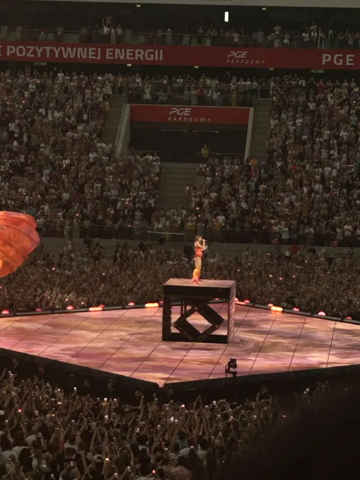The performer alone on a lit platform in the middle of the stadium floor