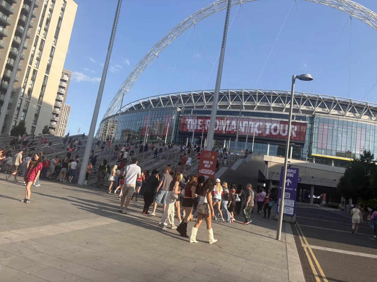 Wembley Stadium and its arch from the walkway, crowds heading in under a Romantic Tour banner