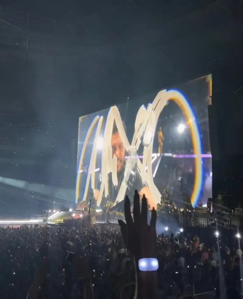 The stage screens and glowing arches seen from the stands