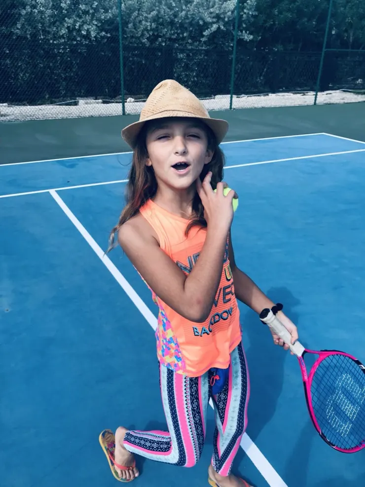 Ruby on the tennis court in a sun hat