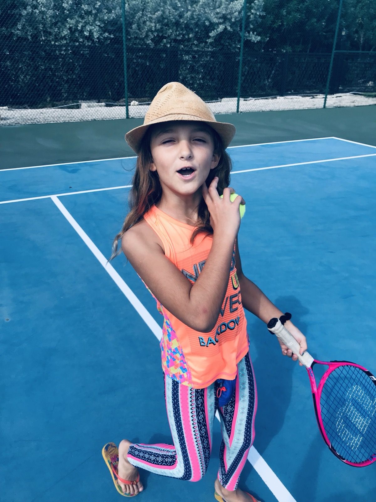 Ruby on the tennis court in a sun hat