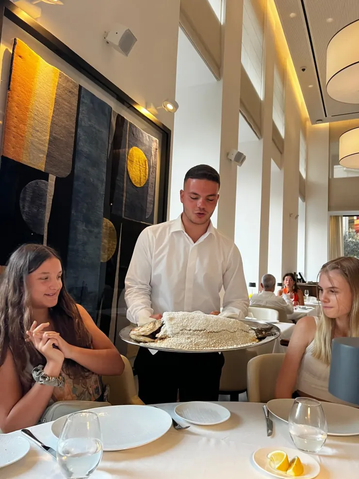 A waiter presenting a whole fish baked in a salt crust at the table