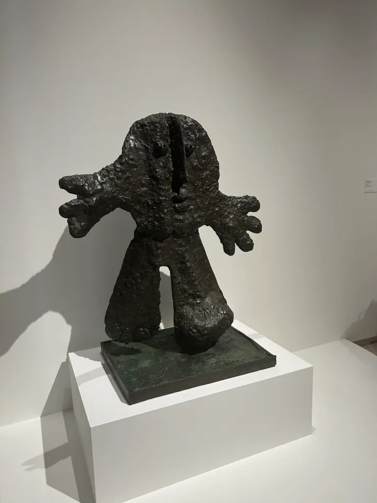 A rough bronze figure sculpture on a gallery plinth