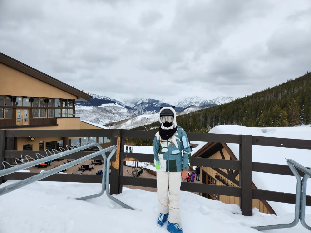 Ruby bundled up against wind and snow with mountains behind