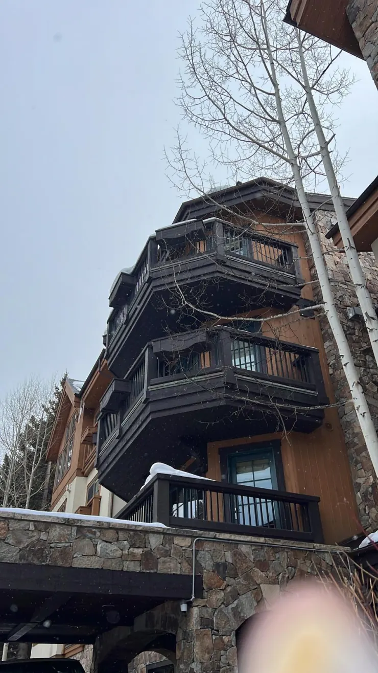 A timber-and-stone lodge building with snow on its balconies