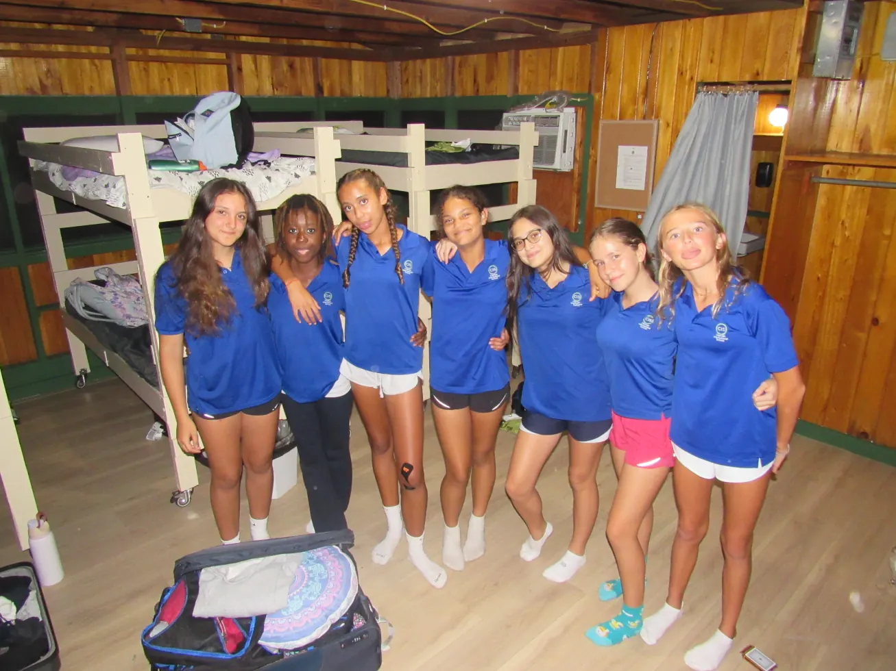 A cabin full of girls posing together by the bunk beds