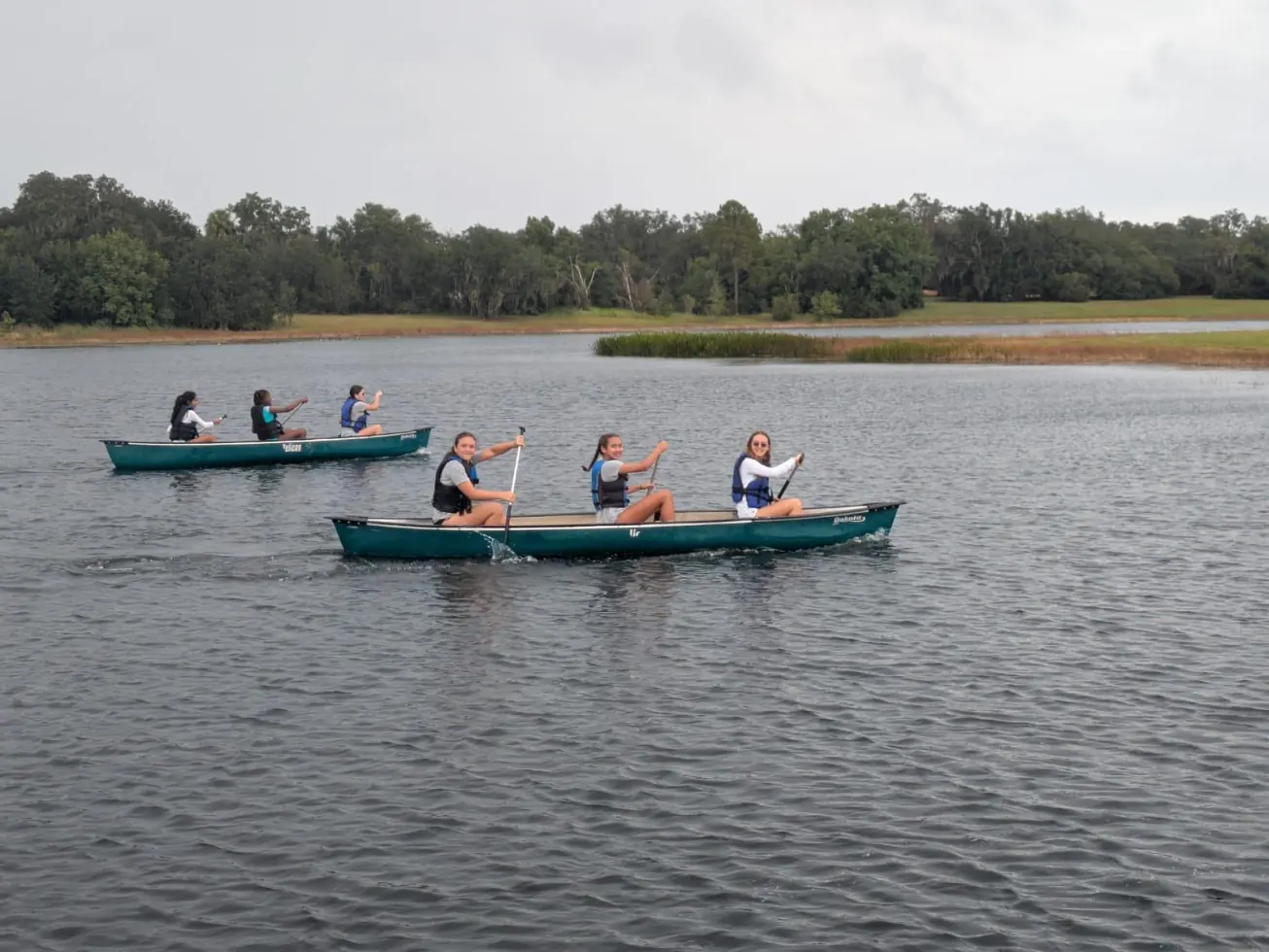 Two canoes of campers paddling across a lake