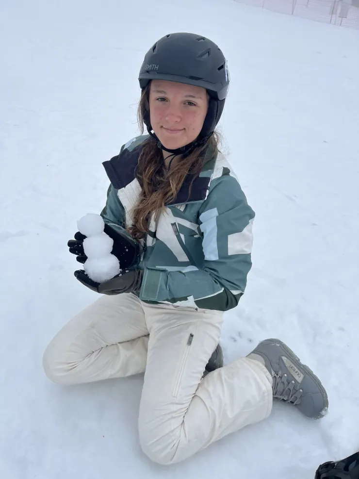 Ruby kneeling in the snow making a snowball
