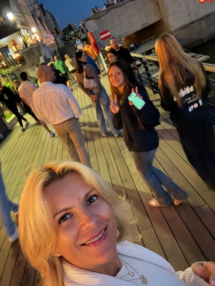 A selfie on a crowded evening boardwalk with the old town crane lit up behind