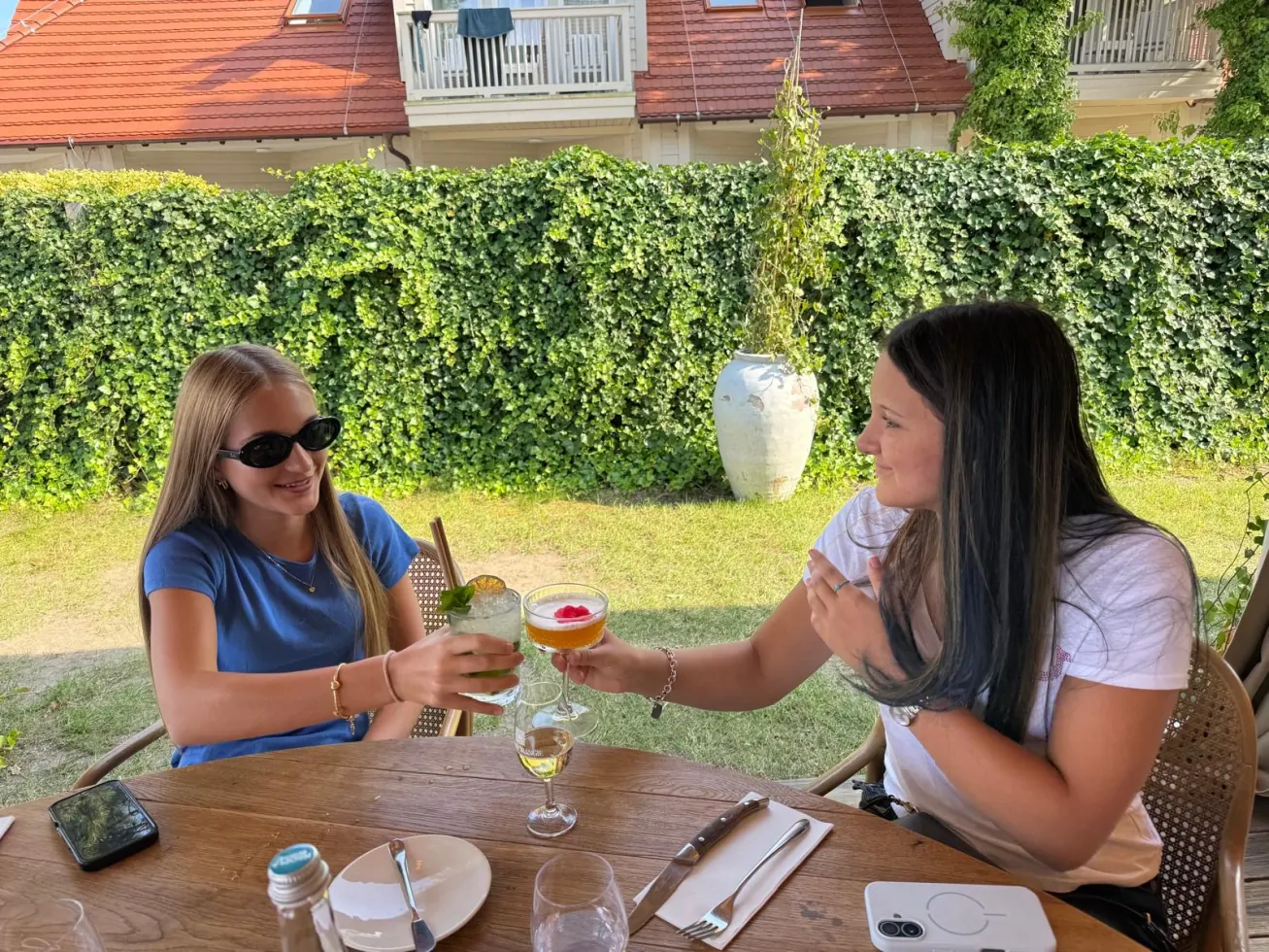 Ruby and a friend toasting drinks at a garden table