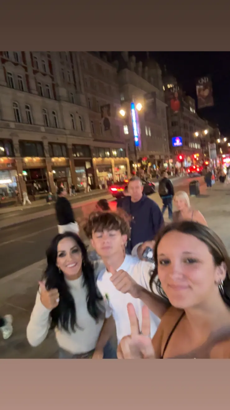 Group selfie on a lit-up street near Leicester Square at night
