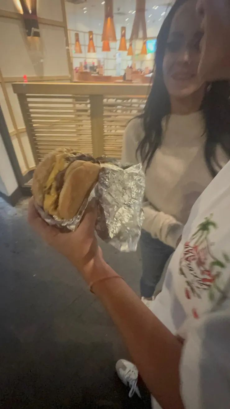 A foil-wrapped burger held up in a fast food restaurant