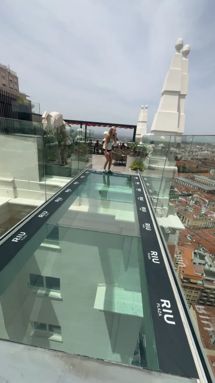 Ruby standing on a glass skywalk high above the rooftops of Madrid