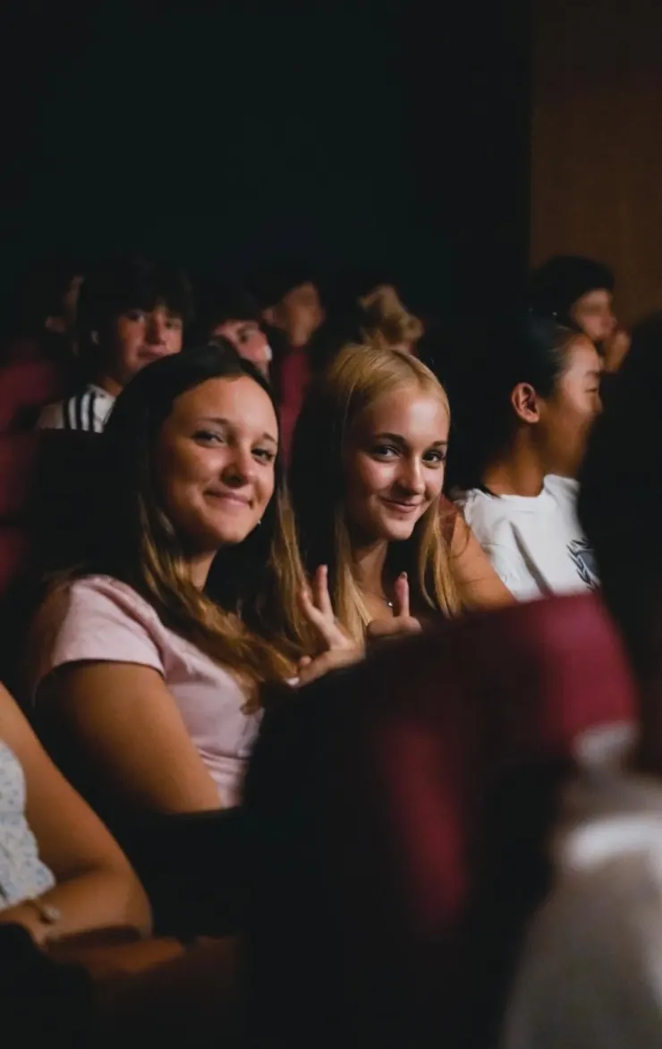 Ruby and a friend in cinema seats giving peace signs