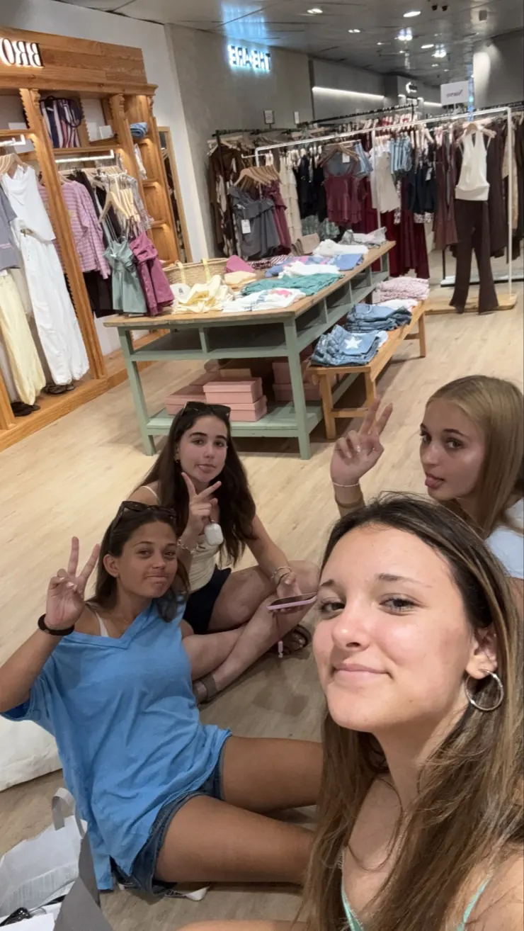 Ruby and friends sitting on the floor of a clothing store, peace signs